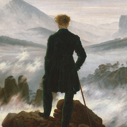 Man in a dark coat standing on a rocky outcrop with a landscape in the background
