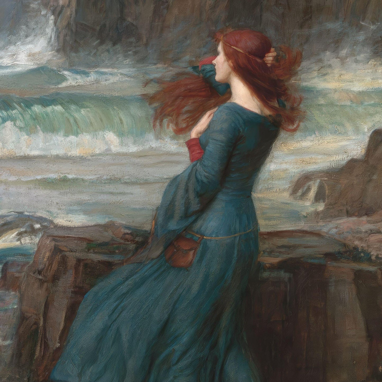 Woman in a blue dress standing on a rocky shore with waves and cliffs in the background