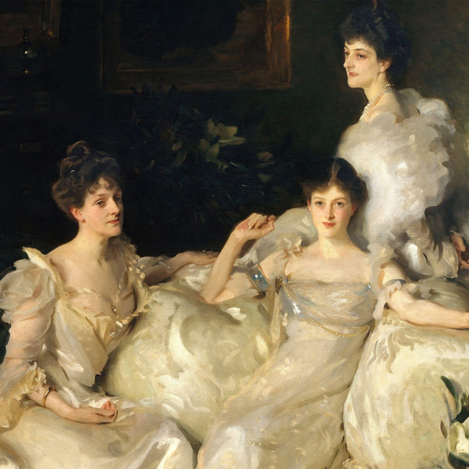 Three women in formal attire sitting together, with a dark background